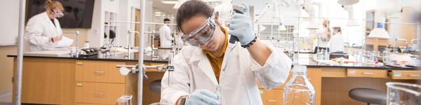 女化学学生在实验室里从烧杯中提取液体.