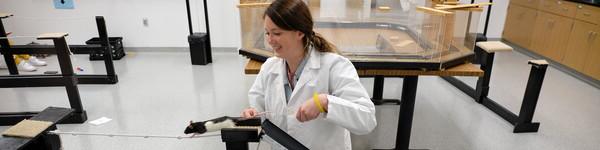 一名女学生在实验室里训练一只黑白相间的老鼠穿过系着的绳子.