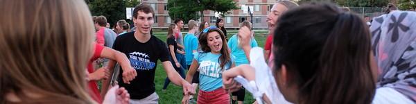 Lots of newly enrolled first-year students dancing in a circle.